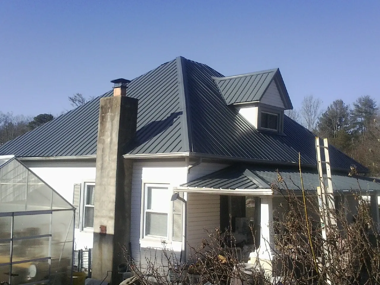 Dark blue standing seam metal roof on a white farmhouse with dormer — Slate & Tile Roof Repair by Roofing Brothers in Warwick