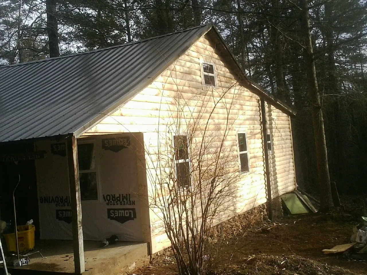 Log siding gable end under a dark metal roof edge in Warwick