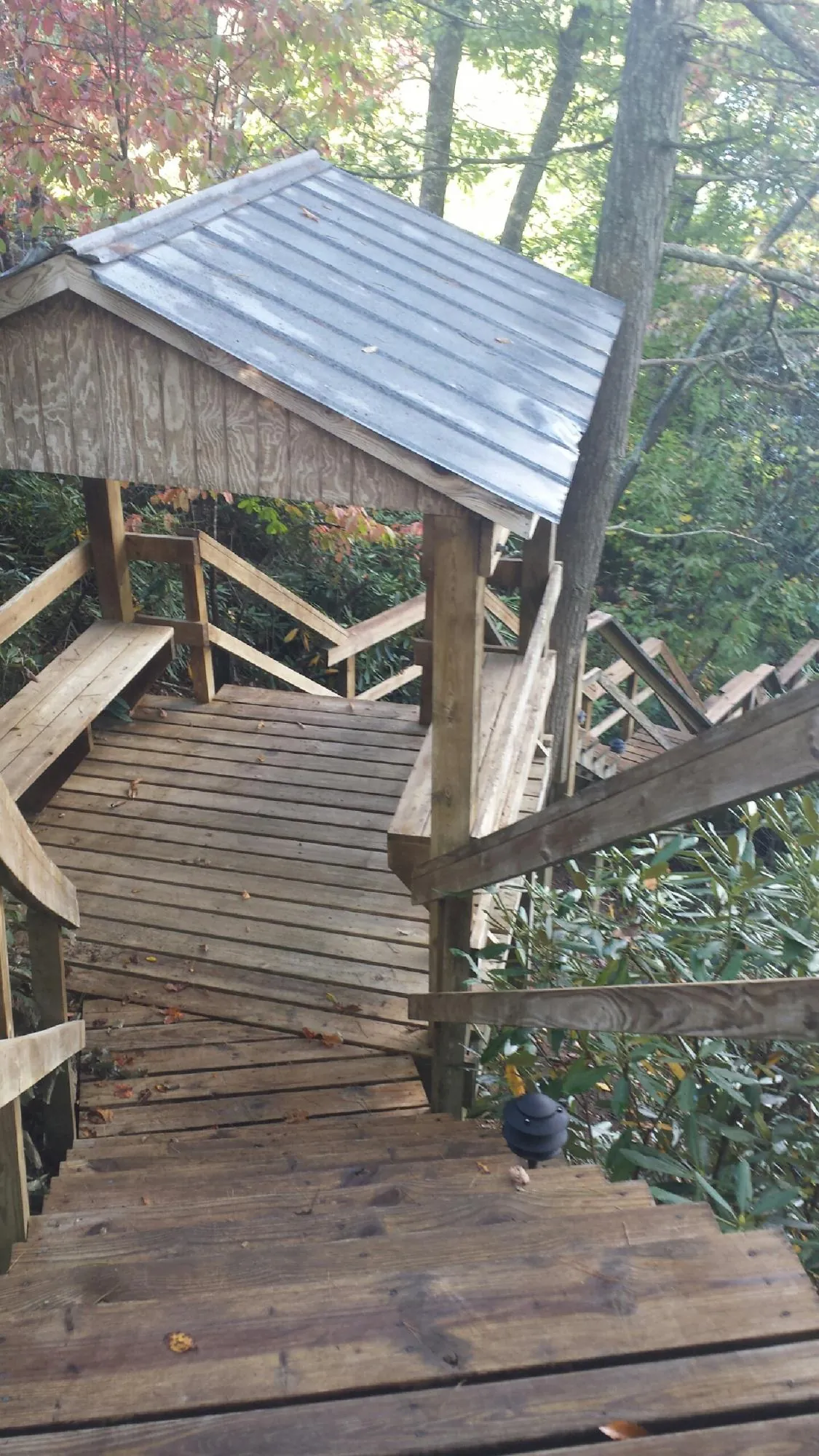 Metal roofed shelter over wooden steps on a wooded walkway — Skylight Repair & Installation work by our crew in Warwick